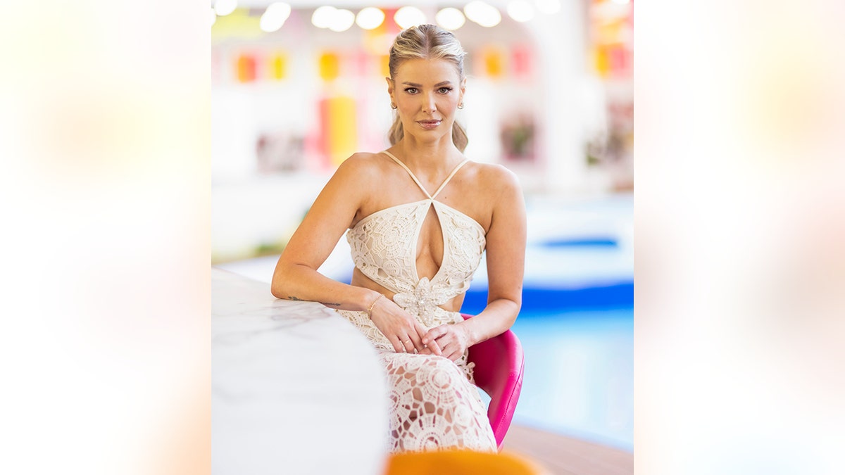 Ariana Madix in a halter lace white dress stares down the camera