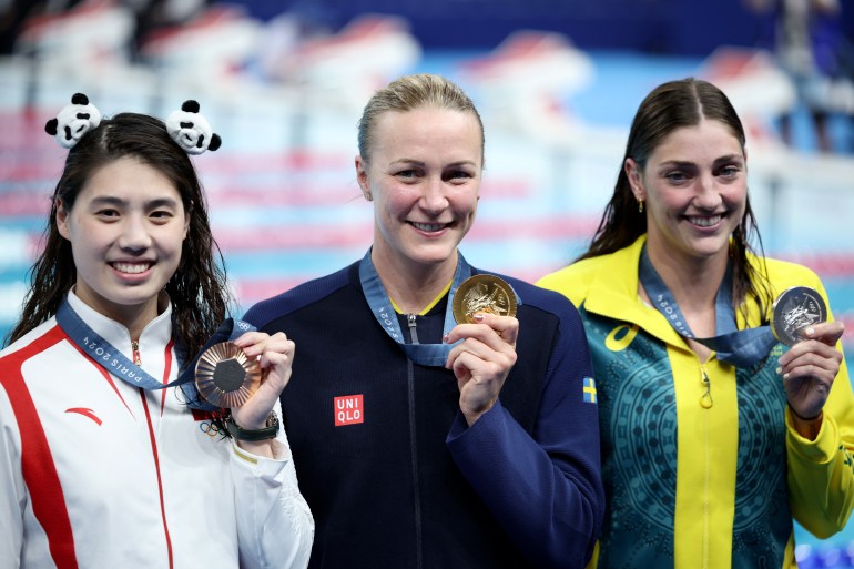 swimmers holding medals.