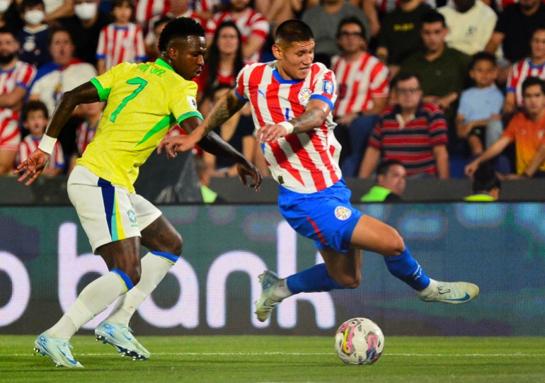 Brazil's forward Vinicius Jr (L) and Paraguay's defender Junior Alonso fight for the ball during the 2026 FIFA World Cup South American qualifiers football match between Paraguay and Brazil at the Defensores del Chaco stadium in Asuncion, on September 10, 2024. (Photo by Daniel DUARTE / AFP)