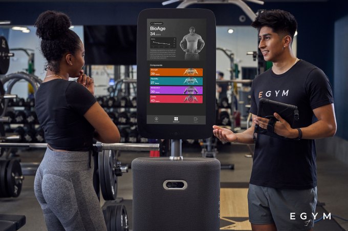 Two people converse amid Egym equipment (Image Credits: EGYM)