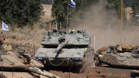 Israeli military vehicles at a gathering site next to the border with Lebanon as seen from an undisclosed location in northern Israel