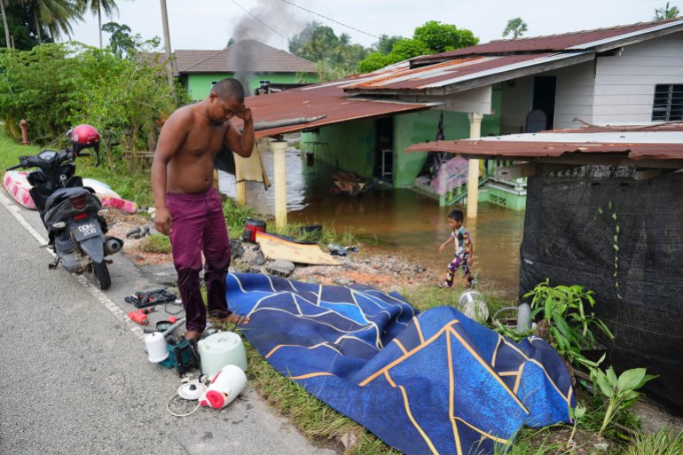 A man dries items he removed from his flooded house in Tumpat, on the outskirts of Kota Bahru in Kelantan state on the east coast of Malaysia, Tuesday, Dec. 3, 2024. (AP Photo/Vincent Thian)