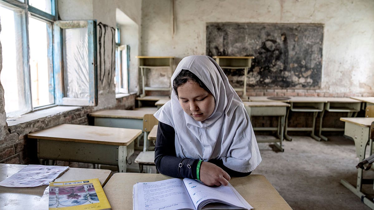 A girl reads a book in her classroom on the first day of the new school year, in Kabul, Saturday, March 25, 2023. Afghanistan’s schools open Wednesday for the new educational year, while thousands of schoolgirls remain barred from attending classes for the third year as the Taliban banned girls from school beyond sixth grade.