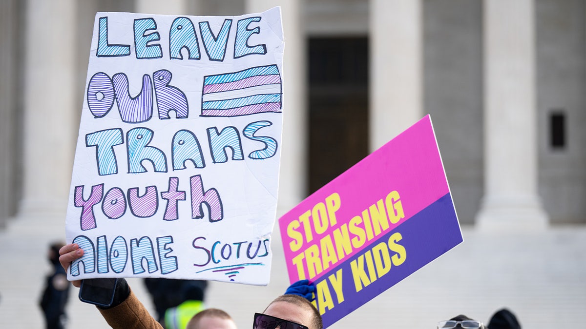 demonstrator with pro-trans signs outside Supreme Court