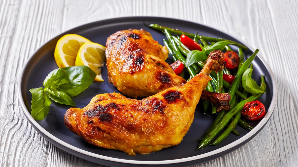 roast chicken legs with green beans, lemon, fried tomatoes, and fresh basil on a plate