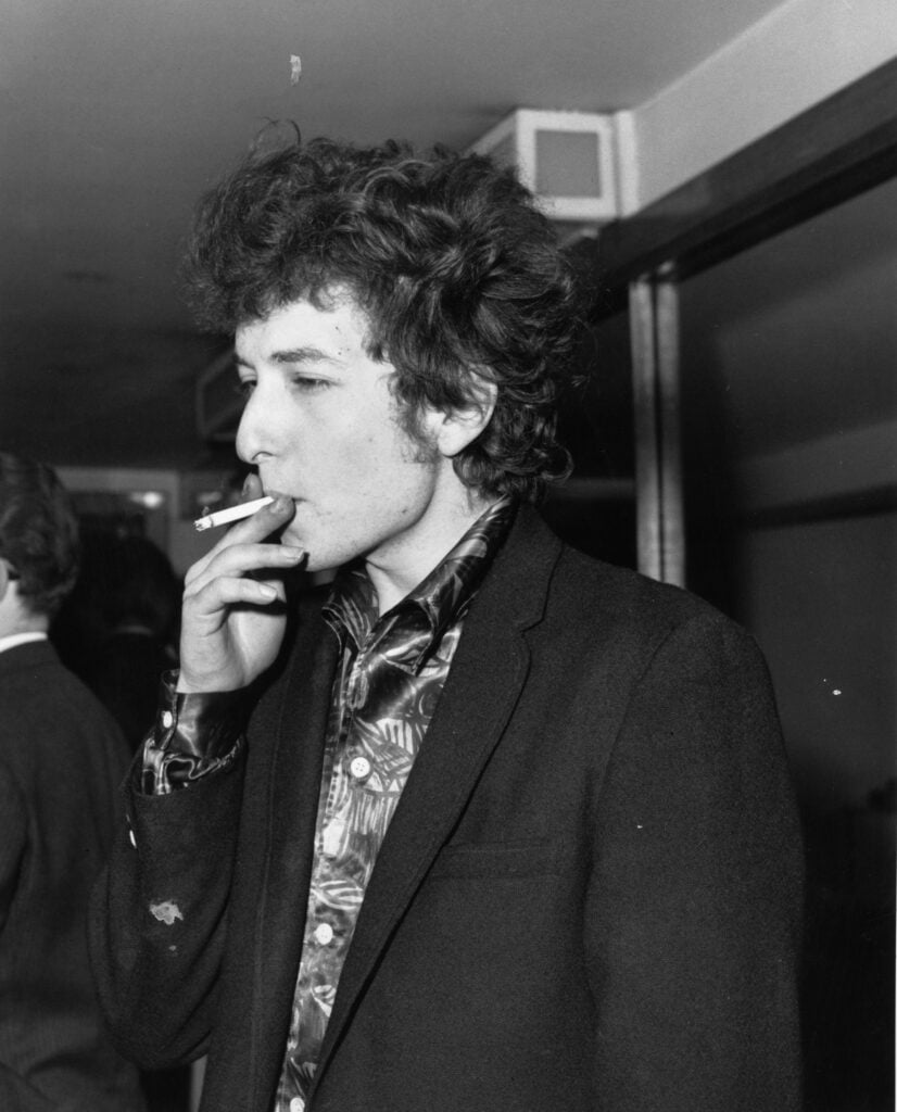 American singer-songwriter Bob Dylan, whose real name is Robert Zimmerman, smoking a cigarette at the Savoy hotel in London. 