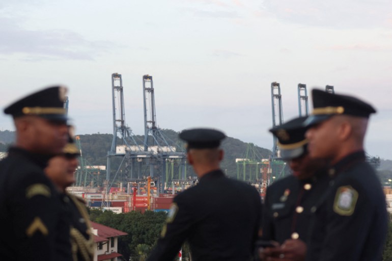 Security officers stand in front of cranes at a ceremony to honor the 25th anniversary of the return of the Panama Canal