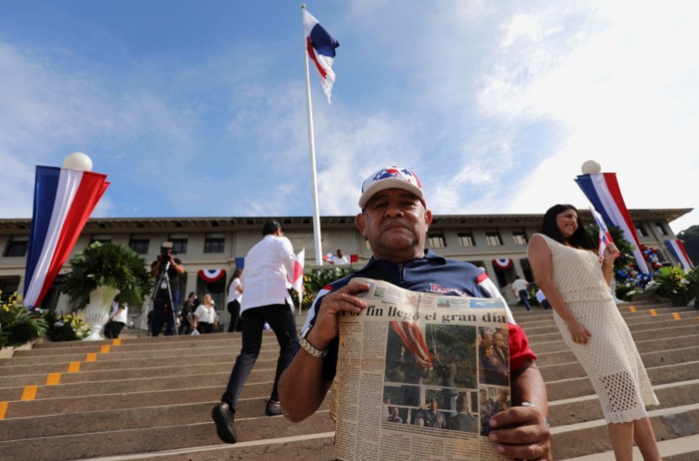 A man holds up a newspaper from 2000 showing the transfer of the Panama Canal