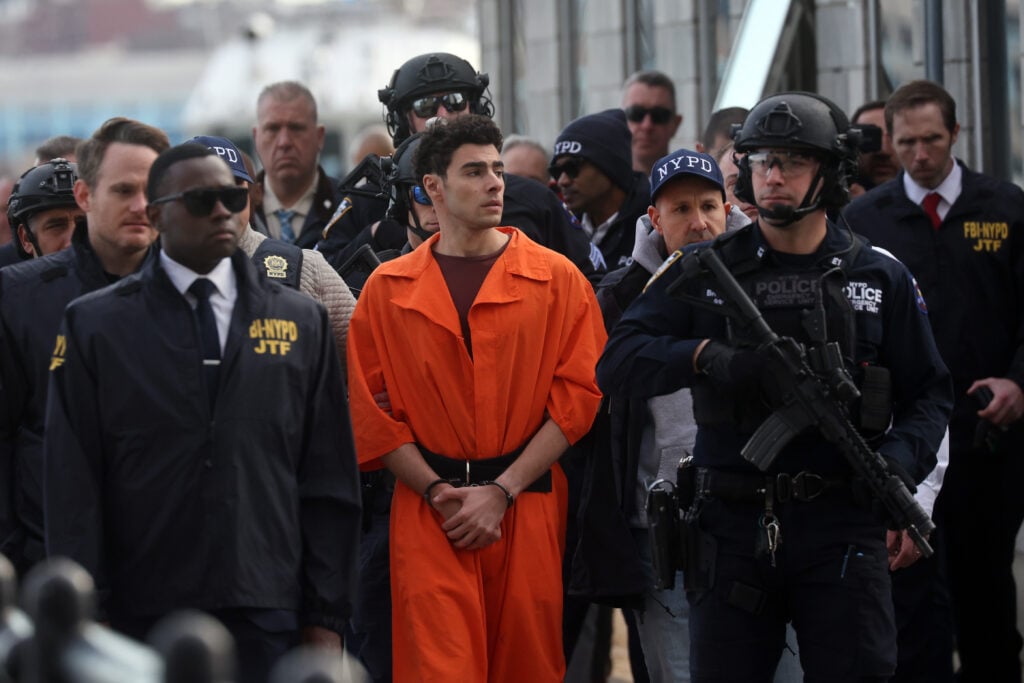 Folk hero Luigi Mangione being escorted by a small army of police during his extradition to New York.