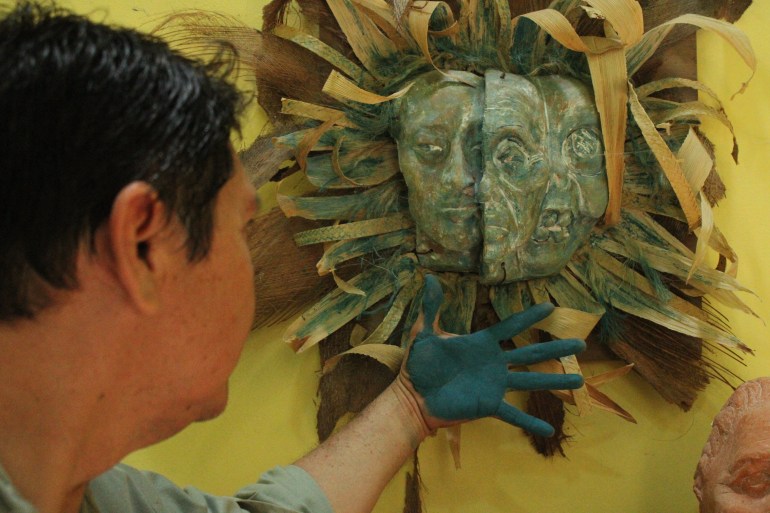 Luis May Ku, 49, admires a three-sided facemask he sculptured, adorned with dried palm leaves and painted in Maya Blue inside his home in Dzan, Yucatán, Mexico, on 9 September, 2024_-1731947746