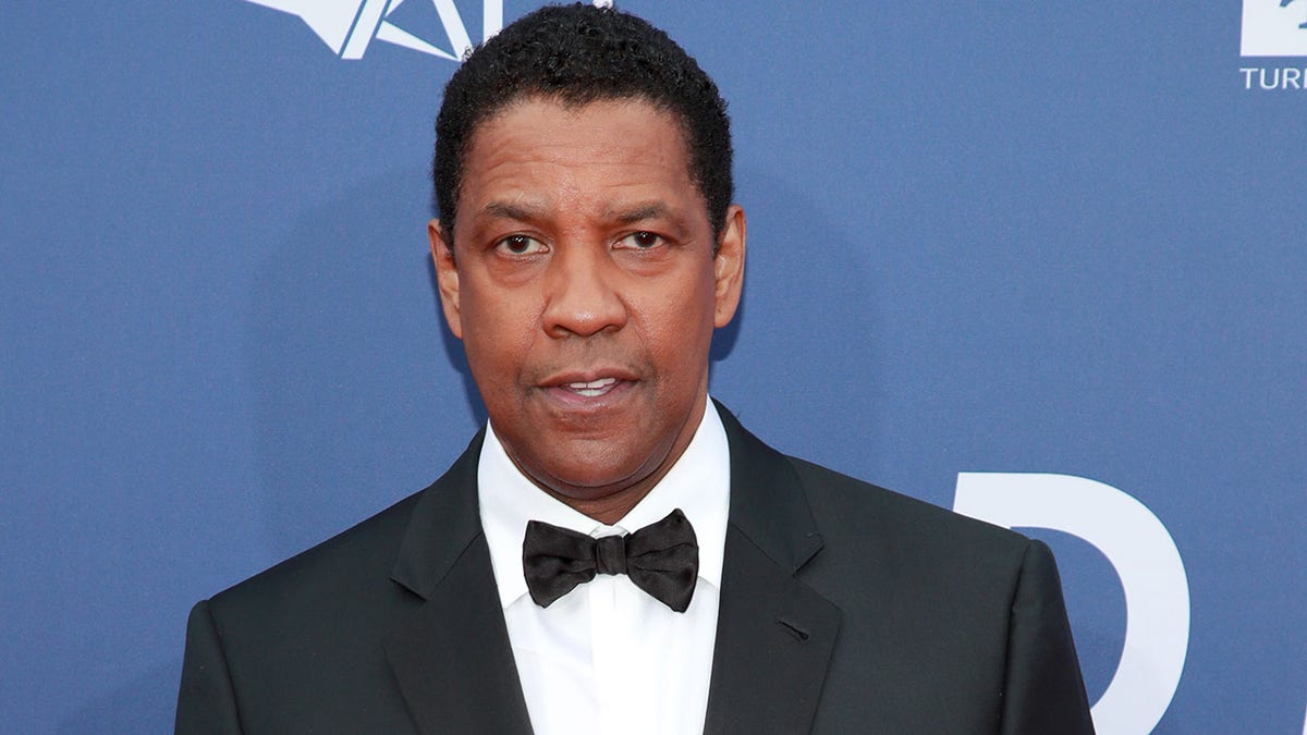 Denzel Washington looks directly in the camera wearing a classic tuxedo