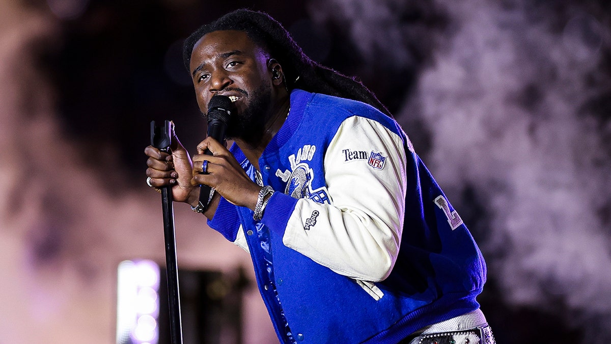 Shaboozey in a Detroit Lions letterman jacket sings on stage