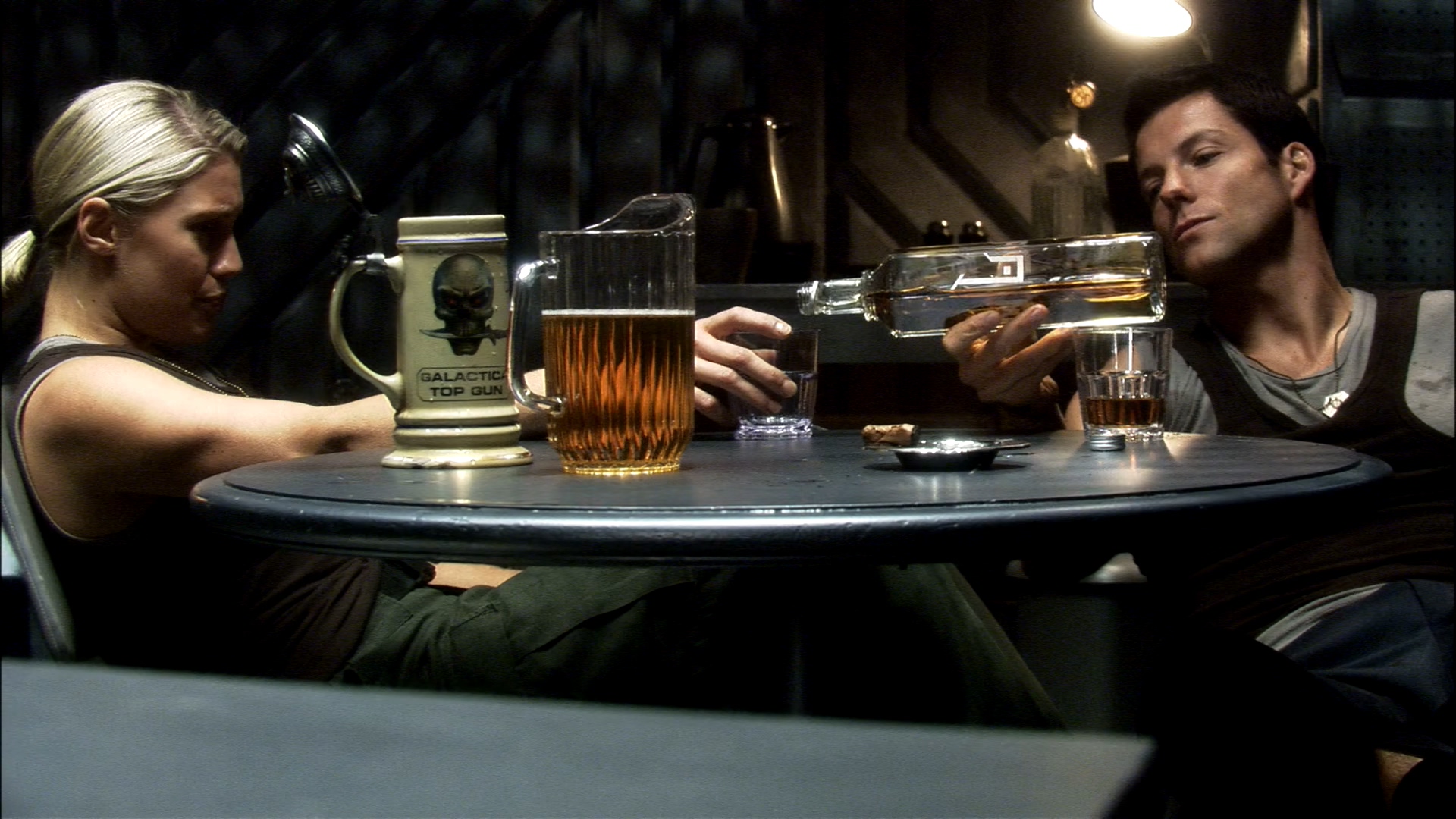 A blonde woman and a brown-haired man sat at a table drinking beer.