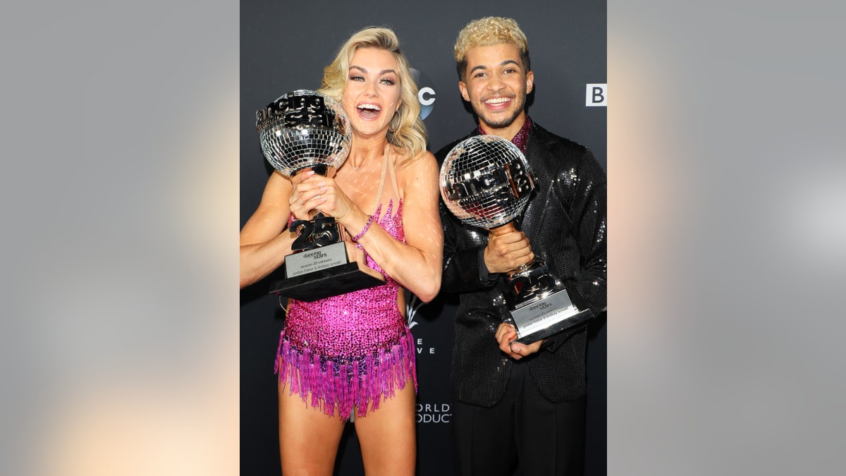 Lindsay Arnold and Jordan Fisher holding mirrorball trophies