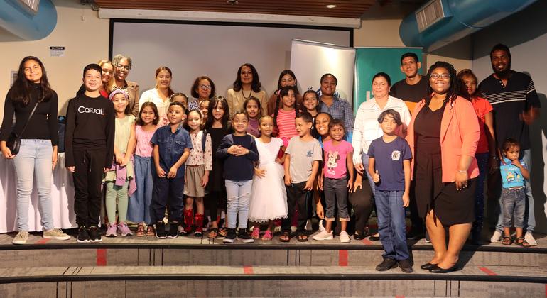 Venezuelan students join their parents for a photo after receiving backpacks and stationery from the UN refugee agency.