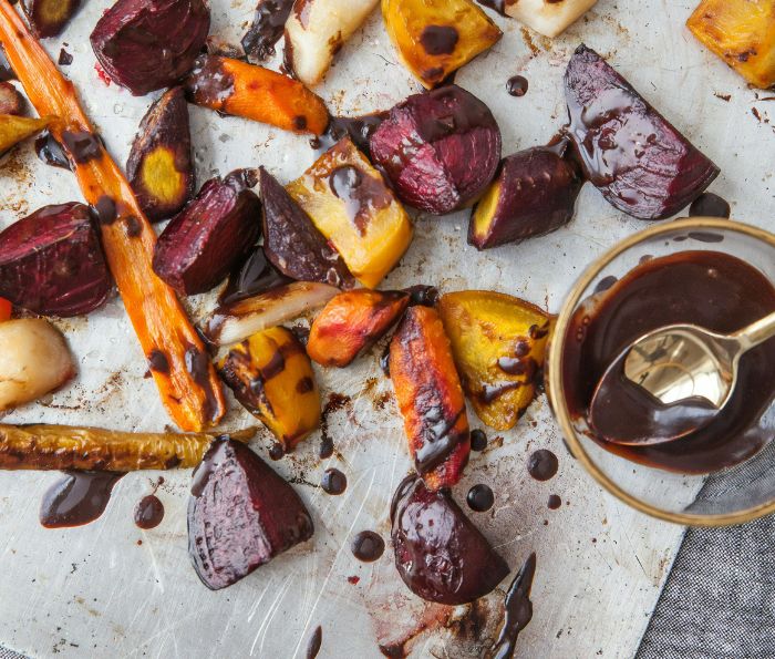 Roast vegetables including carrots and beetroot strewn across a baking sheet