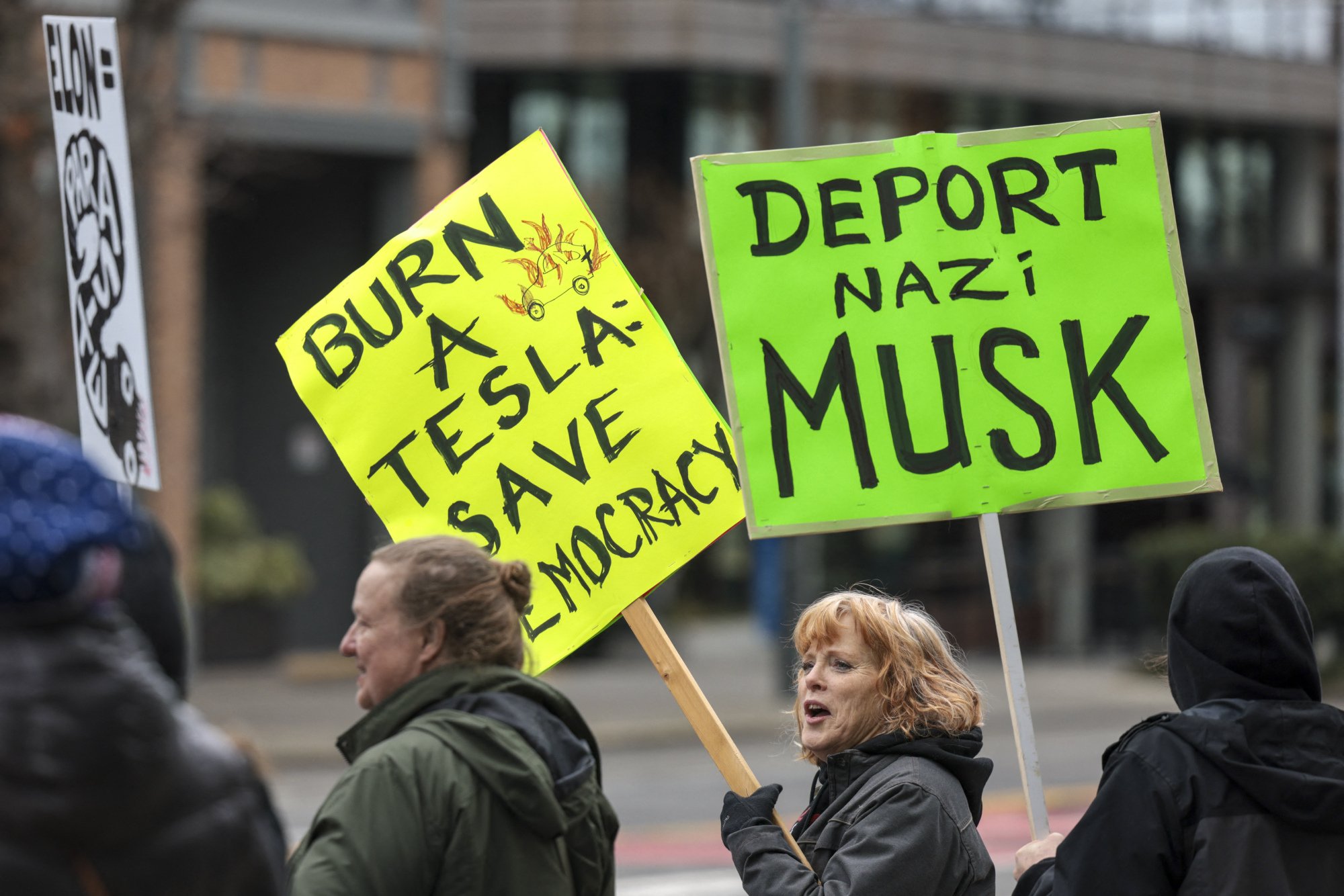 Two protesters hold signs that read 