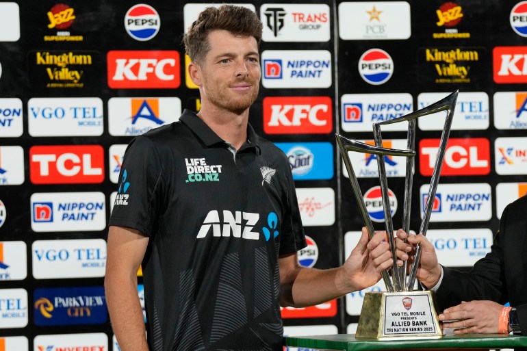 New Zealand's skipper Mitchel Santner receives trophy after winning the tri-series final against Pakistan, in Karachi, Pakistan, Friday, Feb. 14, 2025. (AP Photo/Fareed Khan)