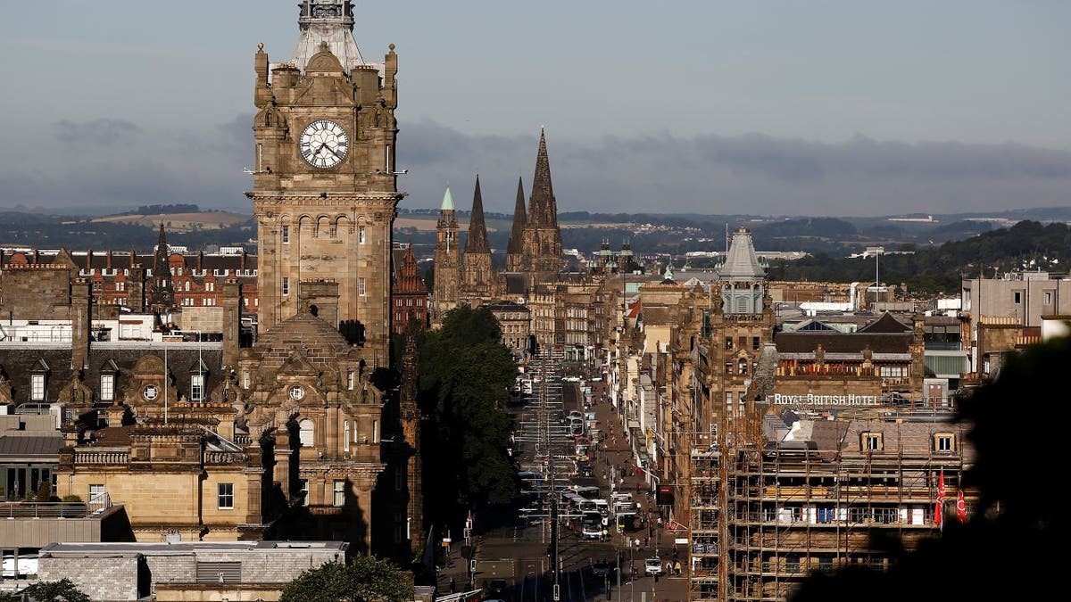 Vehicles pass along Princes Street as the clock tower of Balmoral hotel is seen on the city skyline in Edinburgh, U.K.