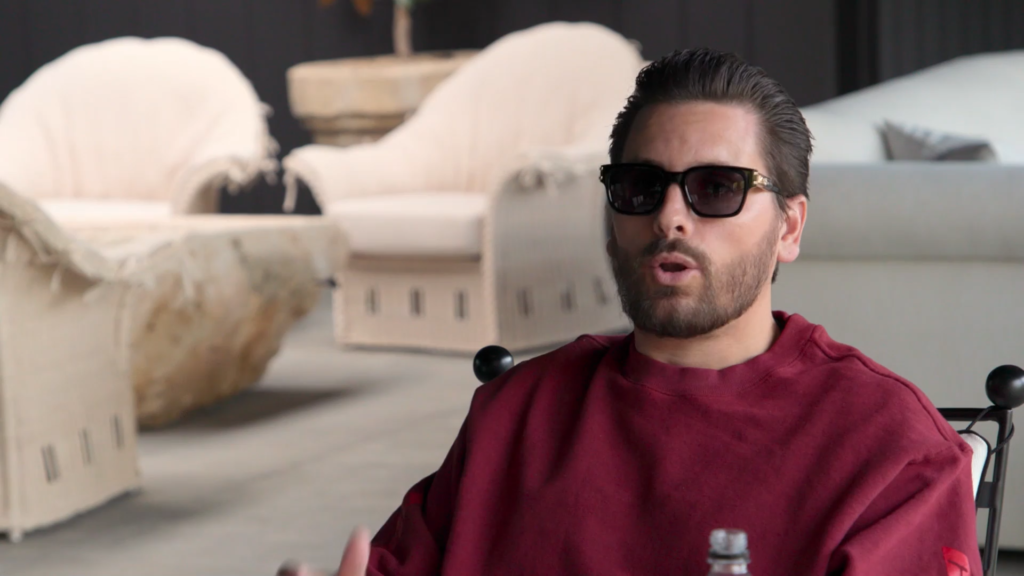 Scott Disick wears glasses adn a maroon sweatshirt.