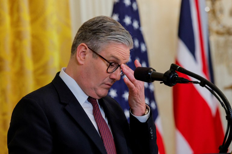 Keir Starmer pushes his glasses up his nose at podium.