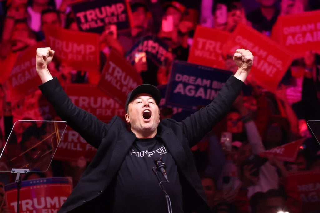 Tesla and X CEO Elon Musk raises his hands as he takes the stage during a campaign rally for Republican presidential nominee, former U.S. President Donald Trump, at Madison Square Garden on October 27, 2024 in New York City. 