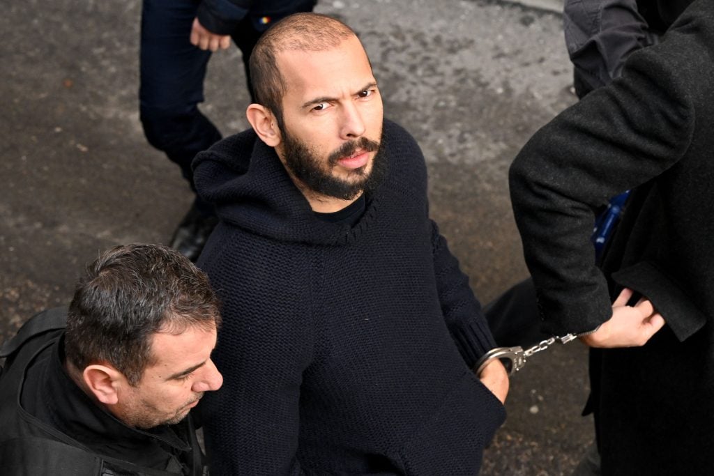 British-US influencer Andrew Tate arrives handcuffed and escorted by police at a courthouse in Bucharest on February 1, 2023 to hear the court decision on his appeal against pre-trial detention for alleged human trafficking, rape and forming a criminal group. 