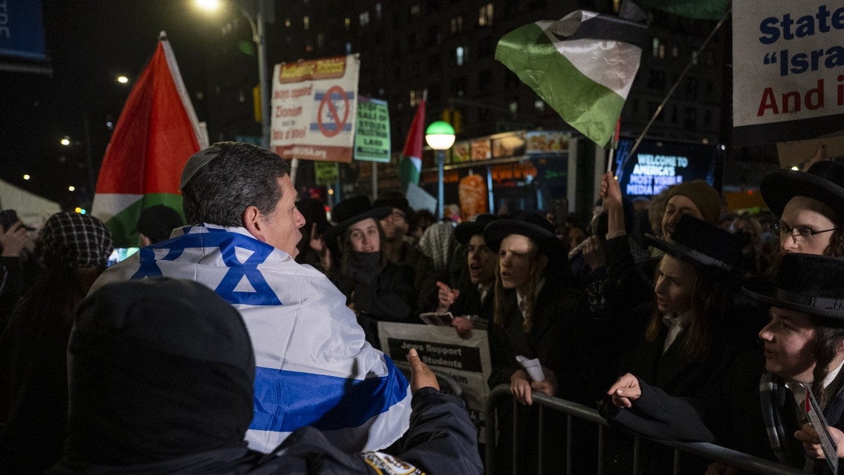 An NYPD officer intervenes as a pro-Israeli counter protester tries to attack Pro-Palestinian demonstrators as they rally outside Columbia University Campus in New York City to protest against former Israeli Prime Minister Naftali Bennett.