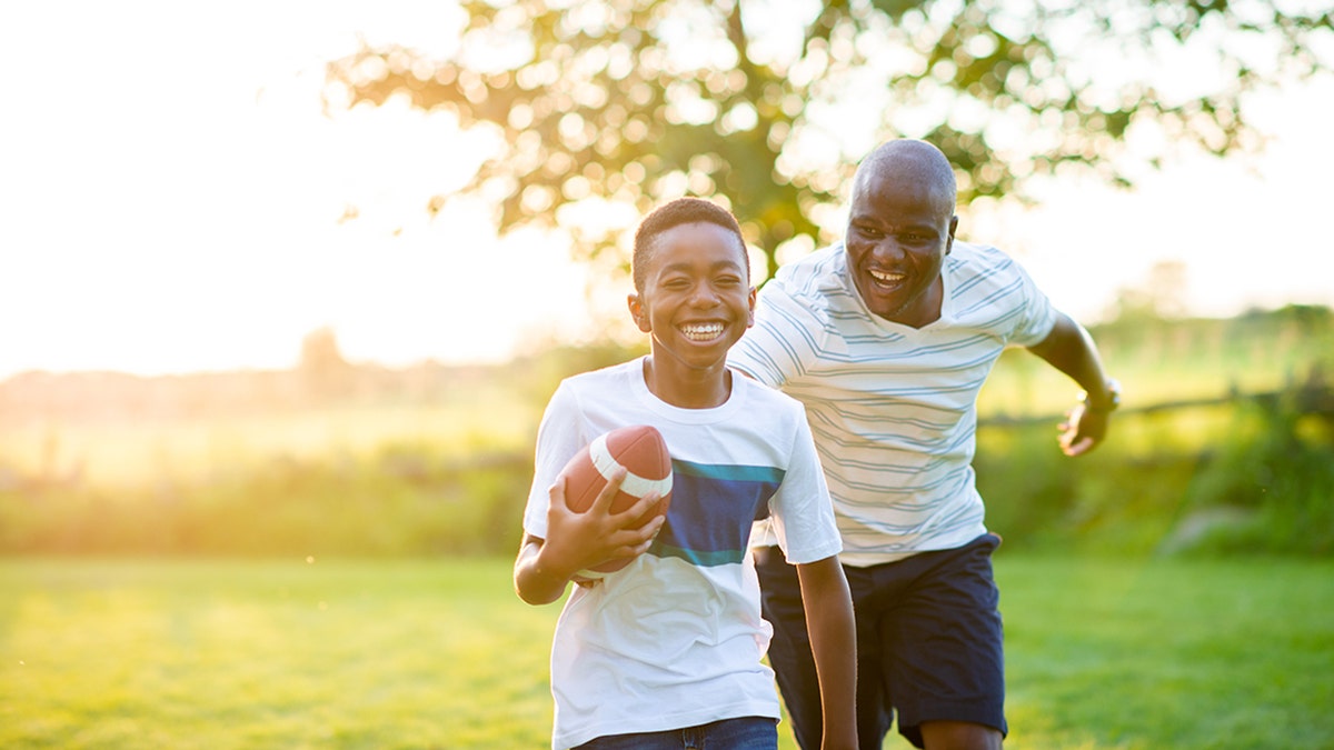 father and son play football outside