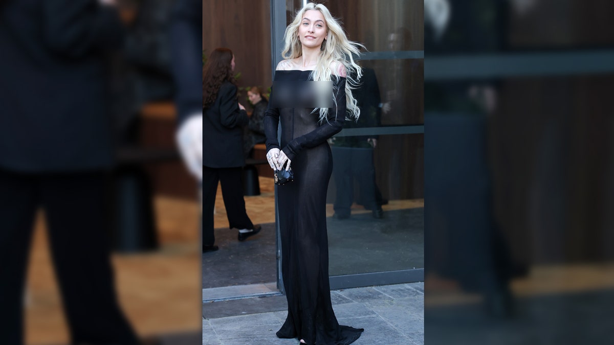 Paris Jackson smiles wearing a black see-through dress.