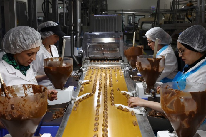Workers with lines of pralines in front of them in Neuhaus’s chocolate factory in Vlezenbeek, Belgium